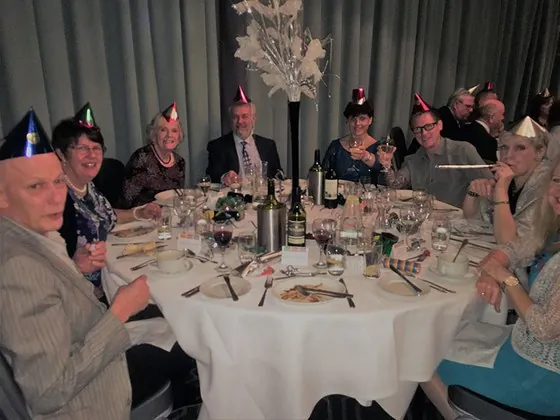 Diners in paper party hats around a dinner table